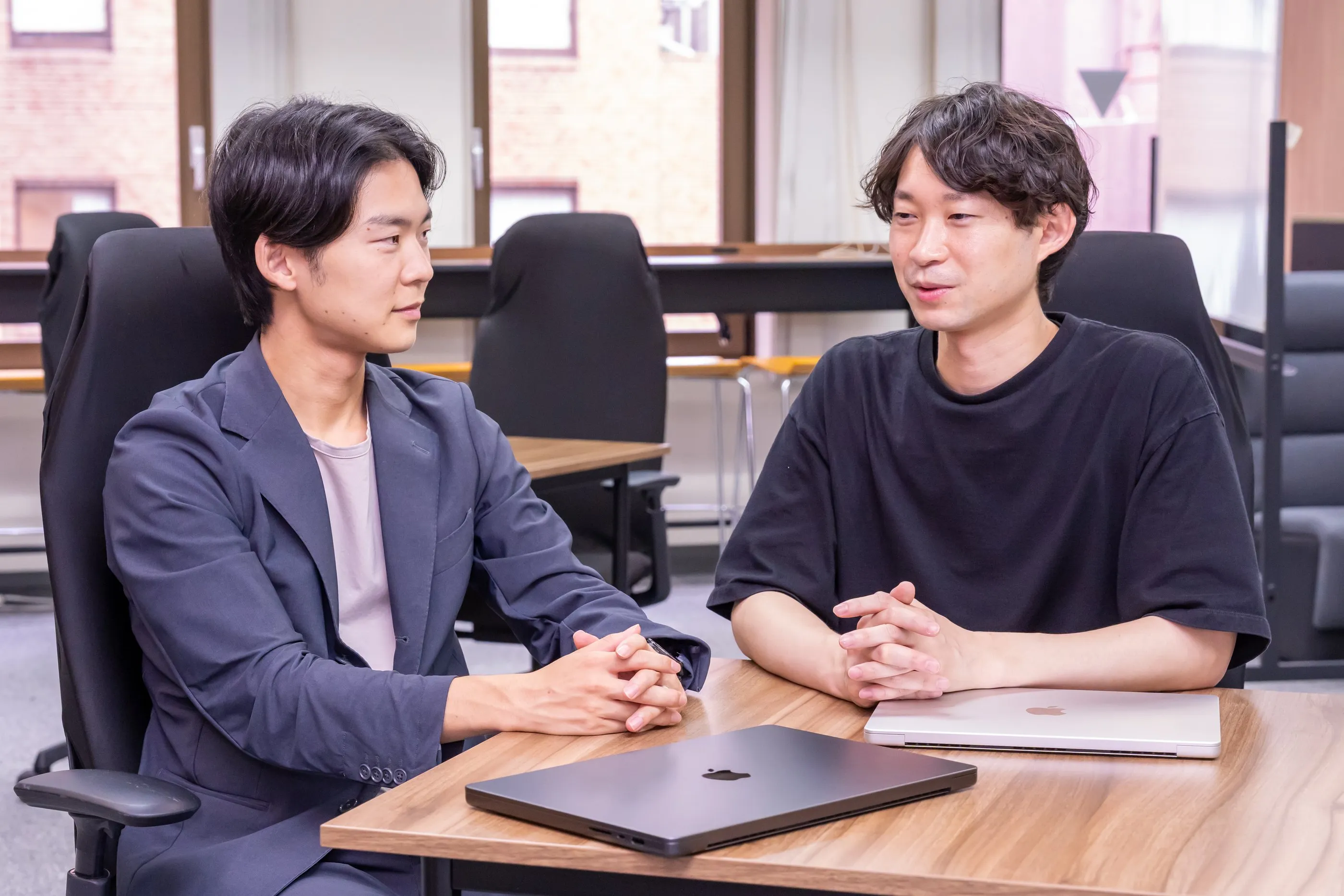 打ち合わせで向き合って話す、代表の村井謙太とプロダクトマネージャーの南部旭彦